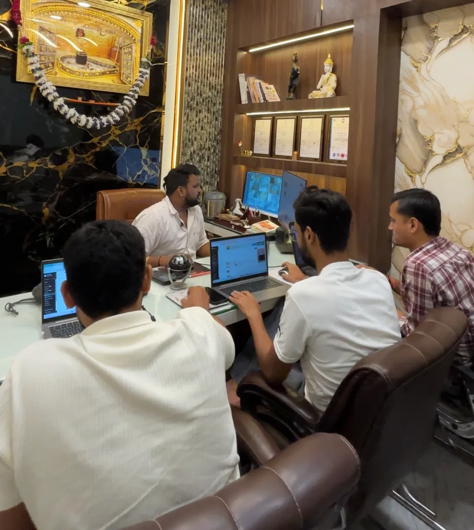 The team sitting around a desk with laptops during an office discussion.